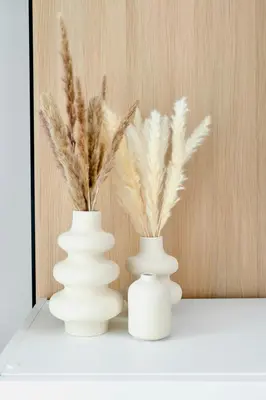 three white vases sitting on a shelf with feathers at New Cozy 1BR in the Heart of the City in Dubai