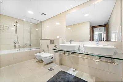 a bathroom with two sinks and a toilet and a shower at Large 1 BR Duplex With Lake View in Dubai