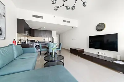 a living room with a blue couch and a tv at Large 1 BR Duplex With Lake View in Dubai