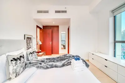 a bedroom with a white bed and a large window at Elite 1 BR in JBR with Marina Views in Dubai