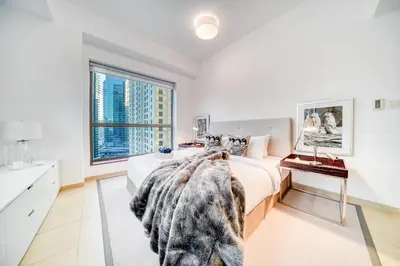 a white bedroom with a bed and a window at Elite 1 BR in JBR with Marina Views in Dubai
