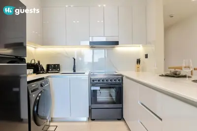 a white kitchen with a stove and a dishwasher at HiGuests - Luxury Apt in the Heart of JVC at Binghatti Nova in Dubai