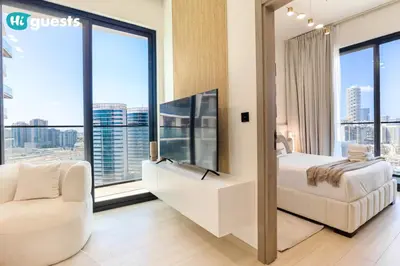 a bedroom with a bed and a chair and large windows at HiGuests - Luxury Apt in the Heart of JVC at Binghatti Nova in Dubai