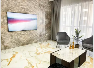 a living room with a chair and a television on a wall at Luxury 4 Bed Apartment in Sadaf 8 on The Walk JBR in Dubai