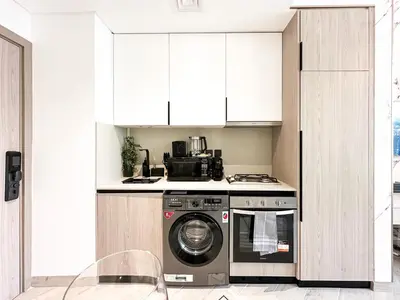 a kitchen with a washing machine and a stove at Indulge in a Regal Retreat at JVC in Dubai