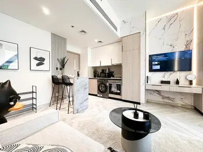a living room with a table and a kitchen at Indulge in a Regal Retreat at JVC in Dubai