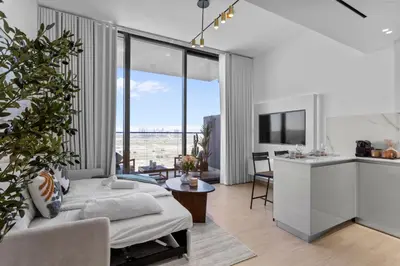 a living room with a bed and a kitchen with windows at Elegant Living in 1 BDR at JVC with Top Amenities in Dubai