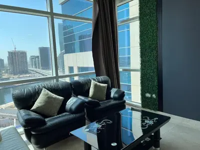a living room with a leather couch and a large window at Apartment in Business Bay, Dubai UAE in Dubai