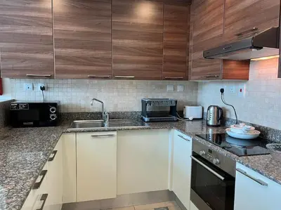 a kitchen with white counters and wooden cabinets at Apartment in Business Bay, Dubai UAE in Dubai