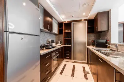 a kitchen with stainless steel refrigerator and wooden cabinets at Chic 1BR Marina View Retreat in Dubai