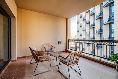 a balcony with chairs and a table with a view at Stylish 2 bedroom apartment with Maid Room I Fairmont South Residence I Palm Jumeirah in Dubai