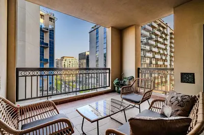 a balcony with chairs and tables and a view of a city at Stylish 2 bedroom apartment with Maid Room I Fairmont South Residence I Palm Jumeirah in Dubai