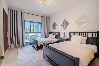 a bedroom with two beds and a window at Stylish 2 bedroom apartment with Maid Room I Fairmont South Residence I Palm Jumeirah in Dubai