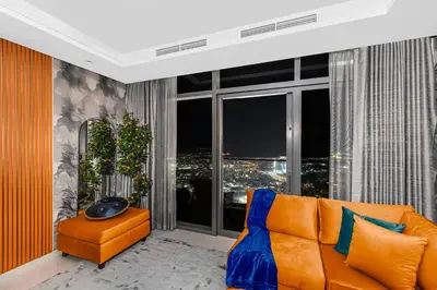 a living room with an orange couch and a large window at 64th floor Skyline Pool with Burj Khalifa View in Paramount Hotel Midtown in Dubai