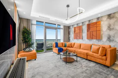 a living room with orange furniture and a large window at 64th floor Skyline Pool with Burj Khalifa View in Paramount Hotel Midtown in Dubai
