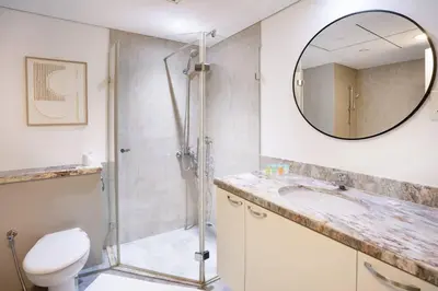 a bathroom with a shower and a toilet and a mirror at Prime Retreats - steps to Grosvenor Hotel Marina in Dubai
