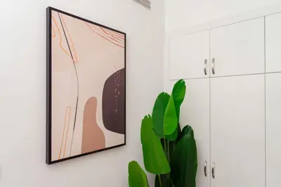 a room with a picture on the wall and a plant at Prime Retreats - steps to Grosvenor Hotel Marina in Dubai