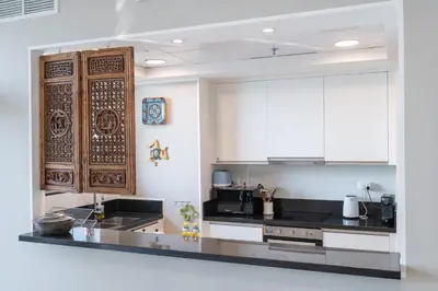 a kitchen with black counters and white cabinets at StayShort - Cozy 1-Bedroom Haven in Business Bay in Dubai