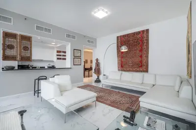 a living room with white furniture and a kitchen at StayShort - Cozy 1-Bedroom Haven in Business Bay in Dubai