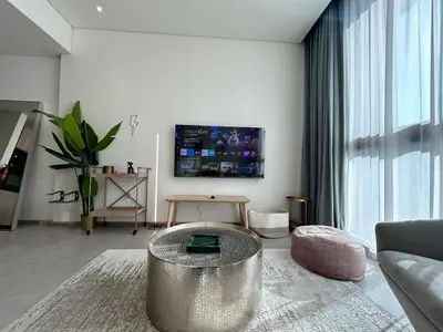 a living room with a couch and a table at Premium 1BHK Apt In Signature living, JVC! Pool view in Dubai