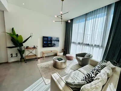a living room with a couch and a large window at Premium 1BHK Apt In Signature living, JVC! Pool view in Dubai