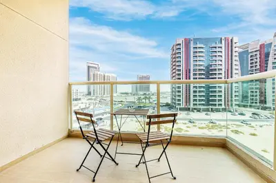 two chairs and a table on a balcony with a view of a city at Luxe Studio with Upgraded Interior in Sports City in Dubai