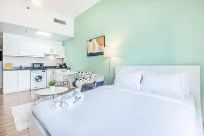 a large white bed in a room with a kitchen at Luxe Studio with Upgraded Interior in Sports City in Dubai