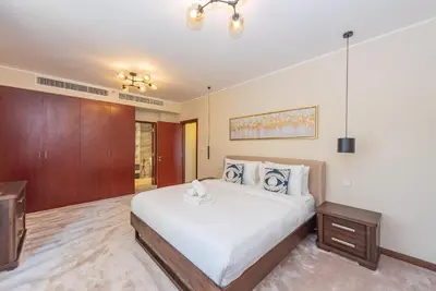 a bedroom with a large white bed and a wooden cabinet at Rimal 4, JBR- Elegant 2 BR in Dubai