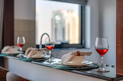 a table with two glasses of red wine and plates at Moderne 1BR with a lovely marina view in Dubai