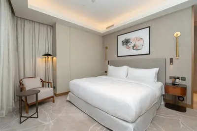 a bedroom with a large white bed and a chair at Spacious 3 Bedroom Apartment in Downtown with Burj Khalifa view in Dubai