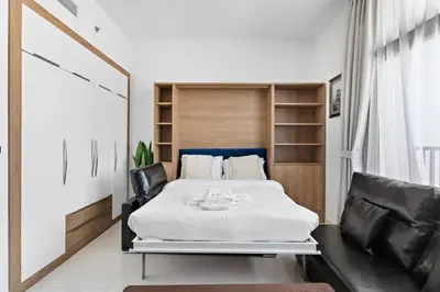 a bedroom with a large bed with black leather chairs at Modern Studio Close To Metro in Dubai