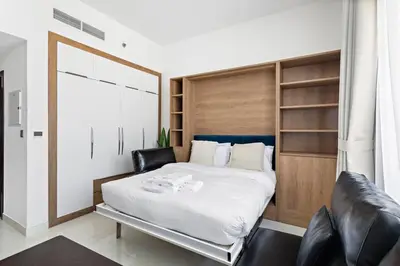 a bedroom with a large white bed and leather chairs at Modern Studio Close To Metro in Dubai
