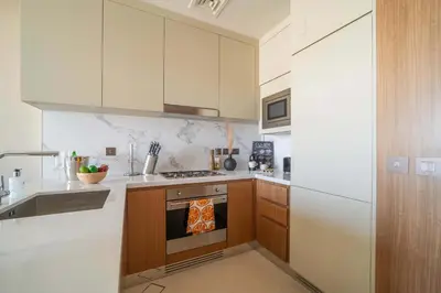 a kitchen with white cabinets and a stove top oven at Frank Porter - The Address Opera Residences in Dubai