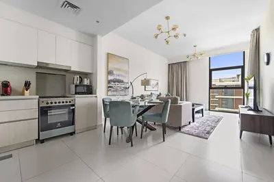 a kitchen and living room with a table and chairs at Modern 1 Br Near To Park in Dubai