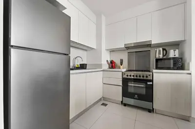 a kitchen with a stainless steel refrigerator and white cabinets at Modern 1 Br Near To Park in Dubai