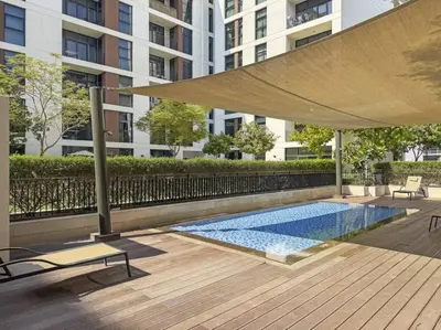 a swimming pool with a large umbrella in front of a building at Modern 1 Br Near To Park in Dubai