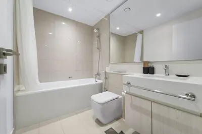 a bathroom with a toilet and a tub and a sink at Modern 1 Br Near To Park in Dubai