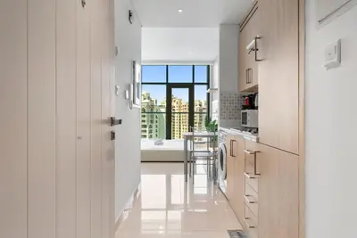 a kitchen with white cabinets and a view of a bathroom at Seven Palm Hotel with West beach access in Dubai