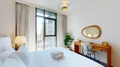 a bedroom with a bed and a desk and a mirror at Creek Edge - Elegant One Bedroom in Creek Habour in Dubai