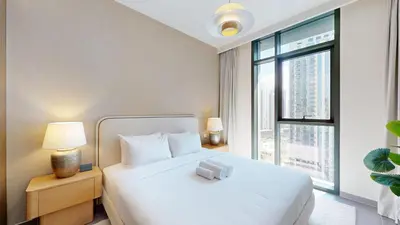 a bedroom with a white bed and a large window at Creek Edge - Elegant One Bedroom in Creek Habour in Dubai