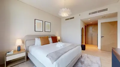 a bedroom with a large white bed and a table at Palace Residence - Chic Two Bed with Creek View in Dubai