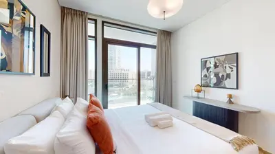 a bedroom with a white bed with a large window at Palace Residence - Chic Two Bed with Creek View in Dubai