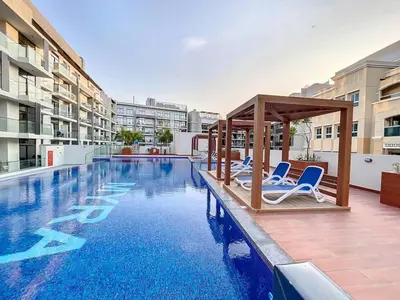 a swimming pool with chairs and a gazebo at Avanos Residence - Captivating Studio in JVC in Dubai