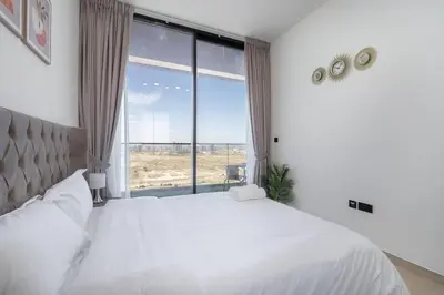 a bedroom with a white bed and a large window at Luxurious 1-Bedroom Oasis l Binghatti Corner, JVC in Dubai