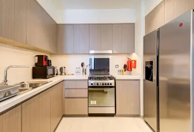 a kitchen with wooden cabinets and a stove top oven at Stylish 2 Bed with Stunning Burj Khalifa View in Downtown in Dubai