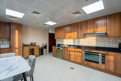 a large kitchen with wooden cabinets and a table at Veer Apartments - 87th Floor Penthouse Full Sea View 5 BHK in Dubai