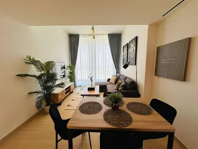 a living room with a dining table and a living room with a couch at Stylish 1br Apt Jvc W Pool & Free Parking in Dubai