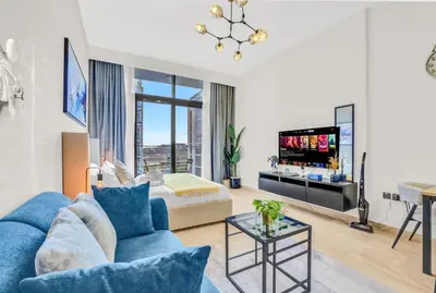 a living room with a blue couch and a tv at Elegant Studio with Pool Access & Private Terrace in Dubai