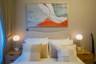 a bedroom with a bed with white pillows and a painting at Elegant Studio with Pool Access & Private Terrace in Dubai