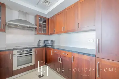 a kitchen with wooden cabinets and a stove top oven at LUX The Fountain View Suite in Dubai